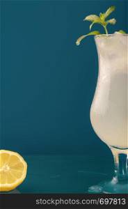 Lemonade glass with ice and mint leaves. Water droplets dripping on the glass surface. Cold drink with lemon slice and ice