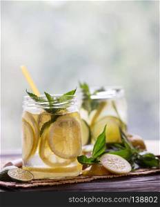 Lemonade with mint and lemon slices on wooden background. Lemonade with mint and lemon slices