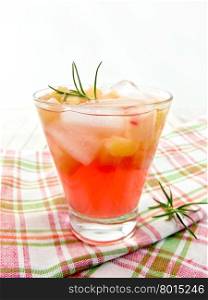 Lemonade with rhubarb and rosemary in a glass on a checkered napkin on a wooden boards background