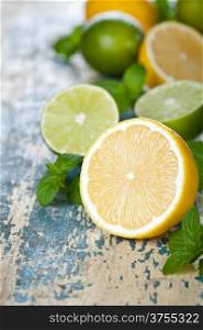 Lemons and limes with fresh mint on table background. Copy space
