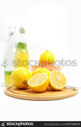 Lemons as ingredients to lemonade, bottles and fruit sqeezer