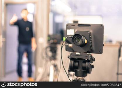 Lens of a film camera in an television broadcasting studio, spotlights and equipment, director in the background