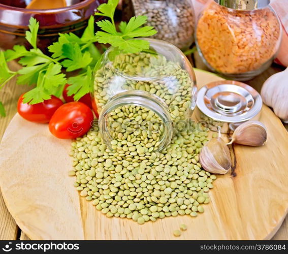 Lentils green in glass jar, parsley, garlic, tomatoes, clay pot, napkin on the background of wooden boards