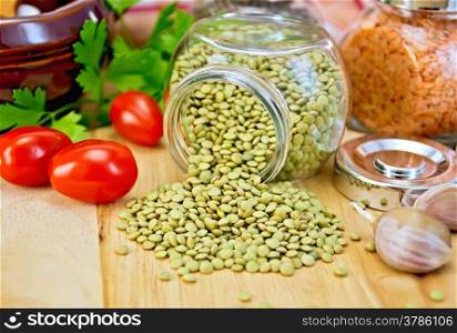Lentils green in glass jar, parsley, garlic, tomatoes, clay pot, napkin on the background of wooden boards