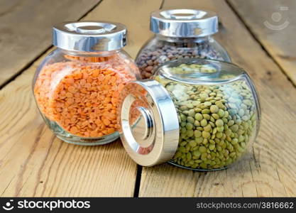 Lentils green, red, brown in the glass jar on a wooden boards background