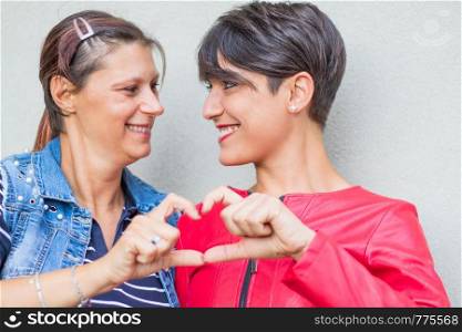 lesbian couple forming heart shape with hands
