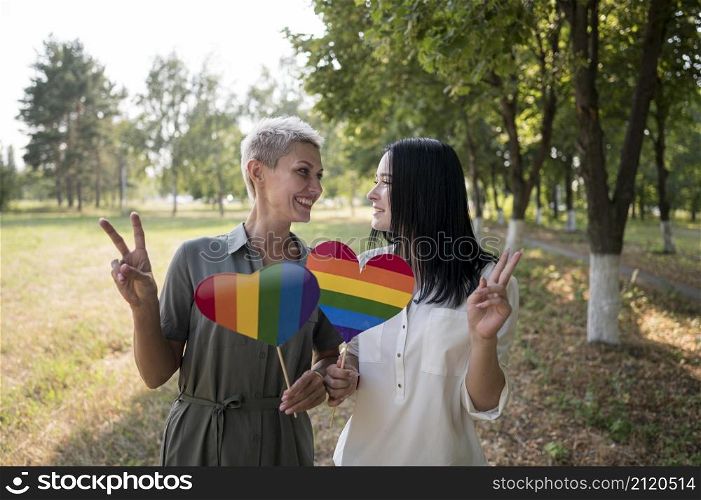 lesbian couple holding lgbt heart shape flag