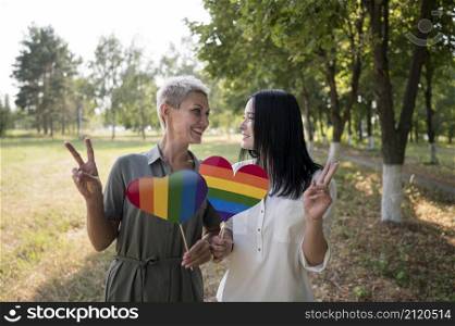 lesbian couple holding lgbt heart shape flag