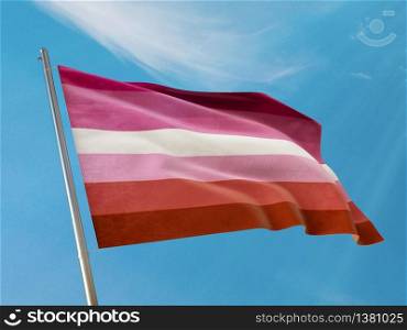 Lesbian flag on a pole waving. Lesbian realistic flag waving against clean blue sky. Close up. Sexual identity pride concept. Photo stock