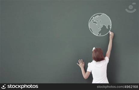 Lesson at school. Cute girl of school age writing with chalk on blackboard