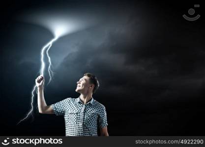 Let it rain. Young man touching illustration of lightning in sky
