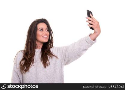 Let me take a selfie!. Happy young woman taking self portrait photography through smart phone over white background.