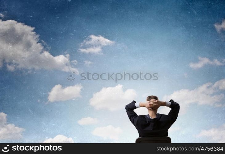 Let me think it over. Rear view of businessman sitting on chair with hands on head