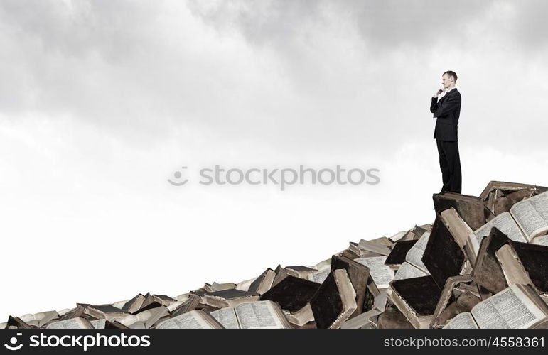 Let me think. Thinking businessman with hand on chin on pile of old books