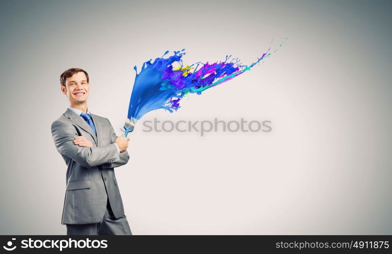 Let&rsquo;s add some color!. Young businessman holding paint brush with colorful splashes