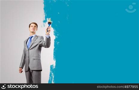 Let&rsquo;s add some color!. Young businessman holding paint brush with colorful splashes