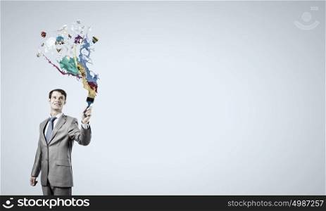 Let&rsquo;s add some color!. Young businessman holding paint brush with colorful splashes