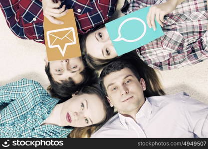 Let&rsquo;s be friends. Group of young smiling people lying on floor in circle with phone symbols