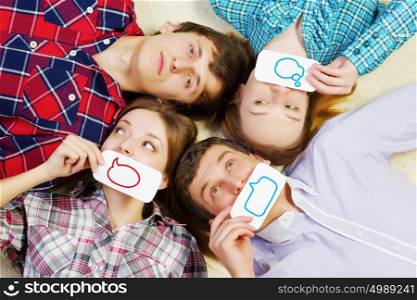 Let&rsquo;s be friends. Group of young smiling people lying on floor in circle with phone symbols