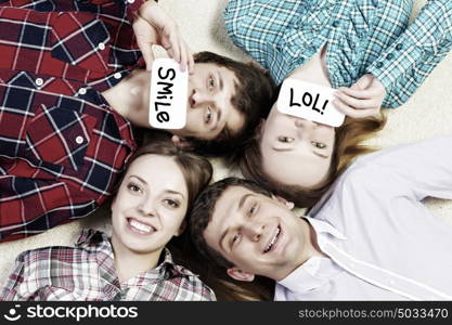 Let&rsquo;s be friends. Group of young smiling people lying on floor in circle with phone symbols