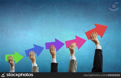 Let&rsquo;s make it grow. Group of business people holding growing graph in raised hands
