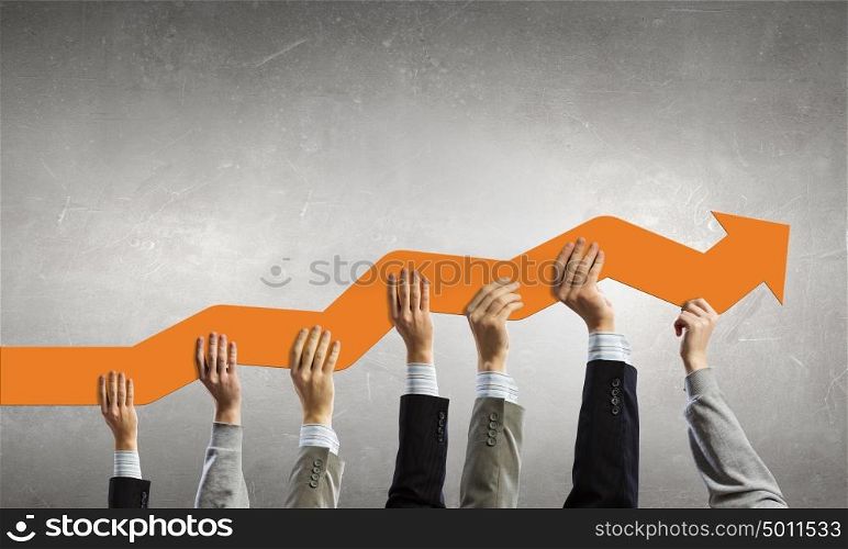Let&rsquo;s make it grow. Group of business people holding growing graph in raised hands