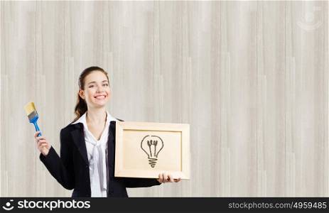 Let&rsquo;s think in colors. Young woman showing wooden frame with drawn bulb