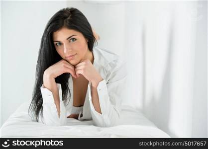 Let's stay in a little while longer - young pretty woman wearing man's shirt on bed. Looking really sexy