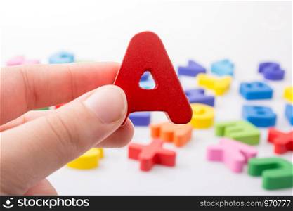 Letter A in hand beside colorful alphabet letter blocks scattered randomly