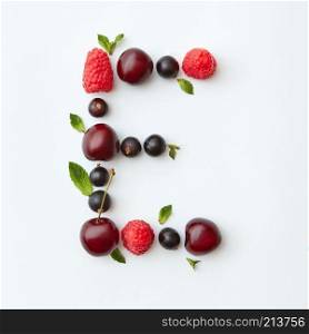 Letter E english alphabet in the form of a pattern of natural organic berries - ripe fresh raspberry, black currant, cherry, green mint leaf isolated on a white background. Top view.. Fresh fruits pattern of letter E english alphabet from natural ripe berries - black currant, cherries, raspberry, mint leaf isolated on a white background. Top view.
