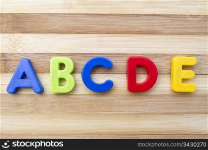 "Letter magnets "ABCDE" closeup on wood background "