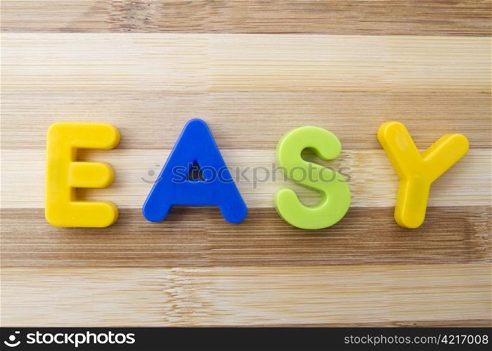 "Letter magnets "EASY" closeup on wood background "