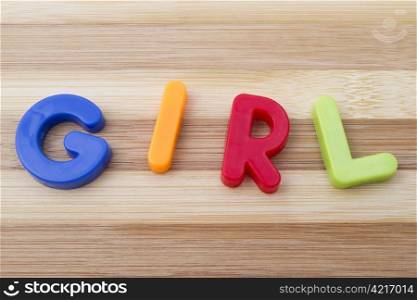"Letter magnets " GIRL" closeup on wood background "