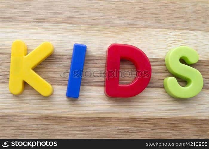 "Letter magnets "KIDS" closeup on wood background"