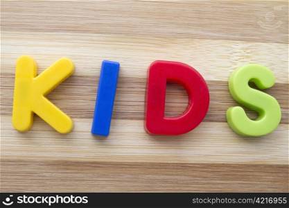 "Letter magnets "KIDS" closeup on wood background"