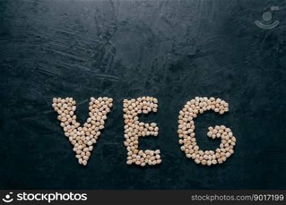 Letter shaped dry garbanzo for vegetarians on dark background with copy space. Natural healthy food concept. Organic seeds. Top view