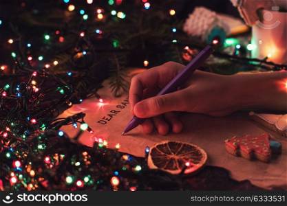 Letter to Santa. Boy&rsquo;s hand closeup, writing a letter to Santa, cristmas background