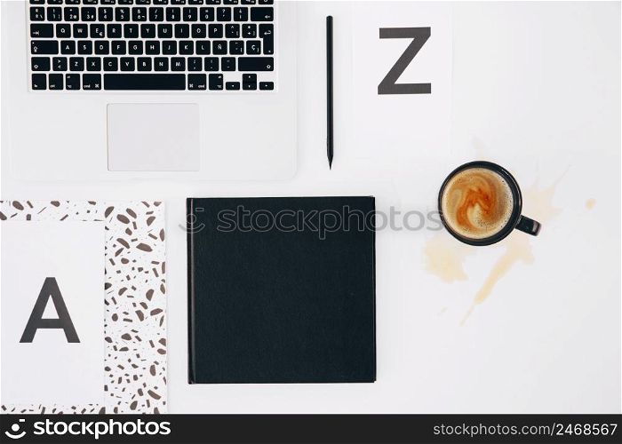 letter z pencil diary laptop spilled coffee cup white backdrop