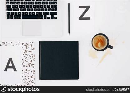 letter z pencil diary laptop spilled coffee cup white backdrop