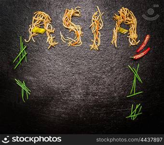 Lettering Asia of asian noodles with chopped chives and red chili on dark slate background, top view place for text
