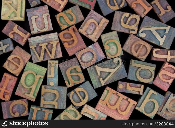 letters of alphabet in vintage wood letterpress printing blocks, placed randomly on black background