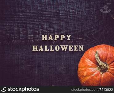 Letters of the alphabet in the form of the inscription Happy Halloween and ripe, bright pumpkin lying on a wooden surface. Close-up. Congratulations to loved ones, family, friends and colleagues. Letters of the alphabet and ripe pumpkin