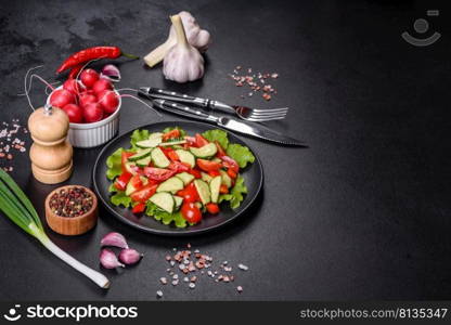 Lettuce, cucumber, spinach, tomato and quail eggs salad with herbs and lemon on black plate on a dark concrete background. Lettuce, cucumber, spinach, tomato and quail eggs salad with herbs and lemon