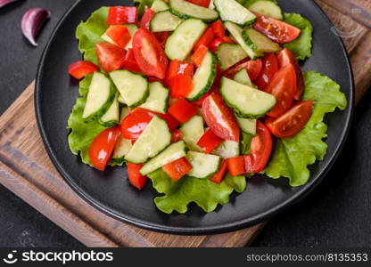 Lettuce, cucumber, spinach, tomato and quail eggs salad with herbs and lemon on black plate on a dark concrete background. Lettuce, cucumber, spinach, tomato and quail eggs salad with herbs and lemon