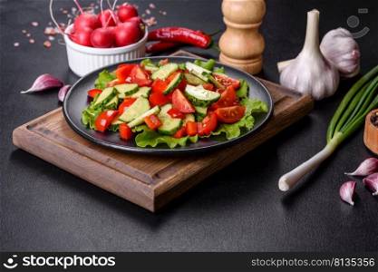 Lettuce, cucumber, spinach, tomato and quail eggs salad with herbs and lemon on black plate on a dark concrete background. Lettuce, cucumber, spinach, tomato and quail eggs salad with herbs and lemon