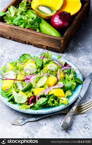 Lettuce salad with mango slices. Healthy vegan salad of vegetables, herbs and mango.Vegan salad