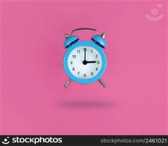 Levitating blue alarm clock on a pink background.. Levitating blue alarm clock on pink background.