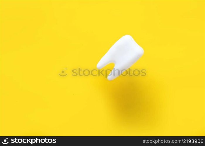 levitating tooth on a yellow background. dentistry advertising concept.