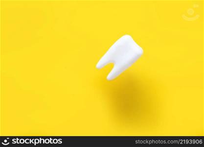 levitating tooth on a yellow background. dentistry advertising concept.