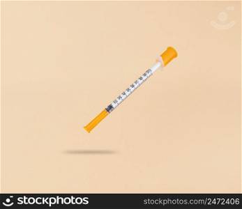 Levitation insulin syringe on a beige background with shadow under it.. Levitation insulin syringe on beige background with shadow under it.